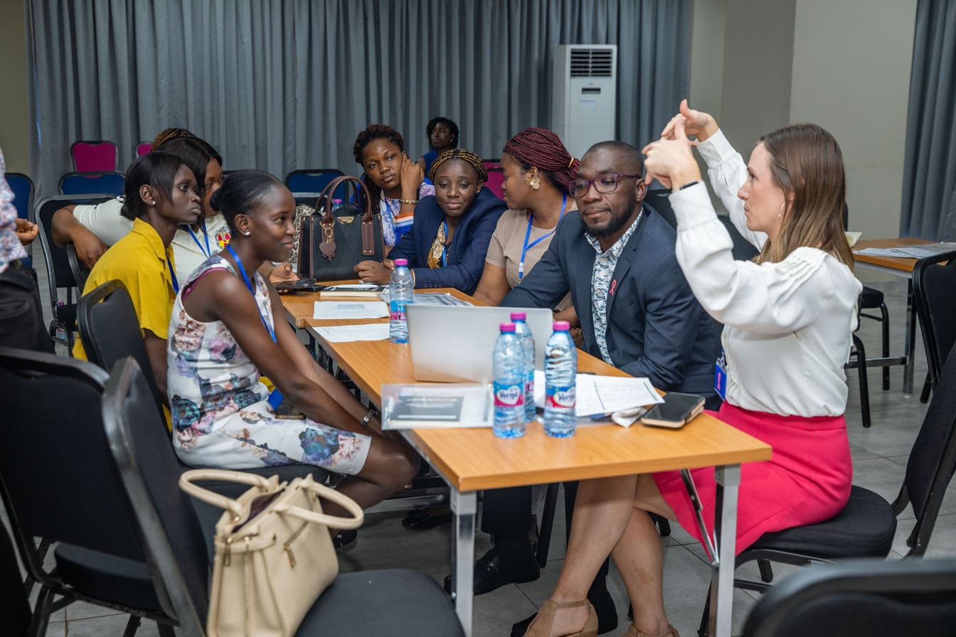 A small group of participants in discussion around a laptop during a COTC Africa breakout session